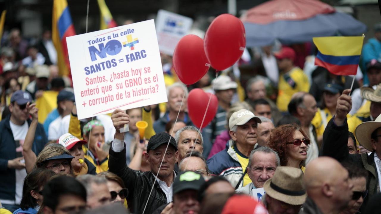 Kritiker des Friedensvertrags und des kolumbianischen Präsidenten Santos halten Protestplakate, Flaggen und rote Luftballons in die Höhe.