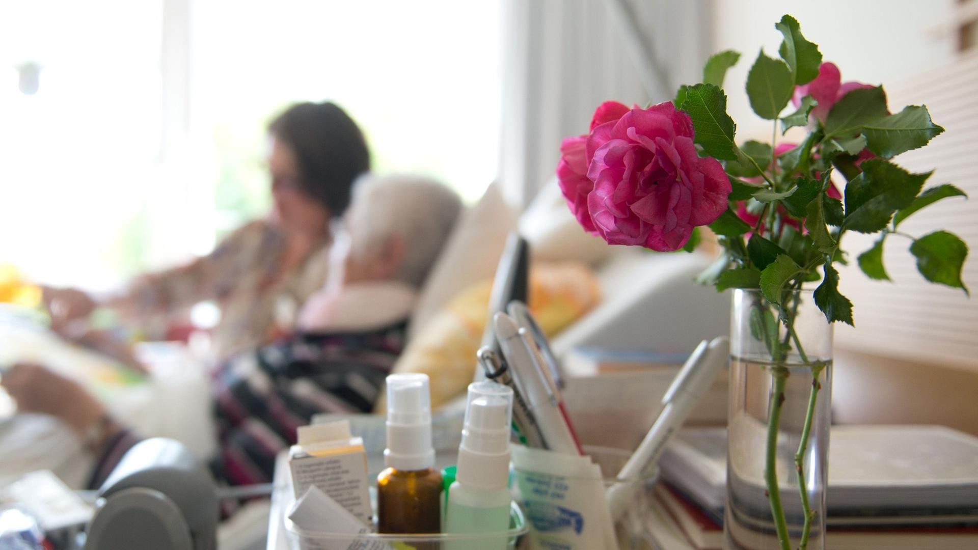 Eine Kunsttherapeutin zeichnet mit einer Frau in einem Hospiz ein Bild.