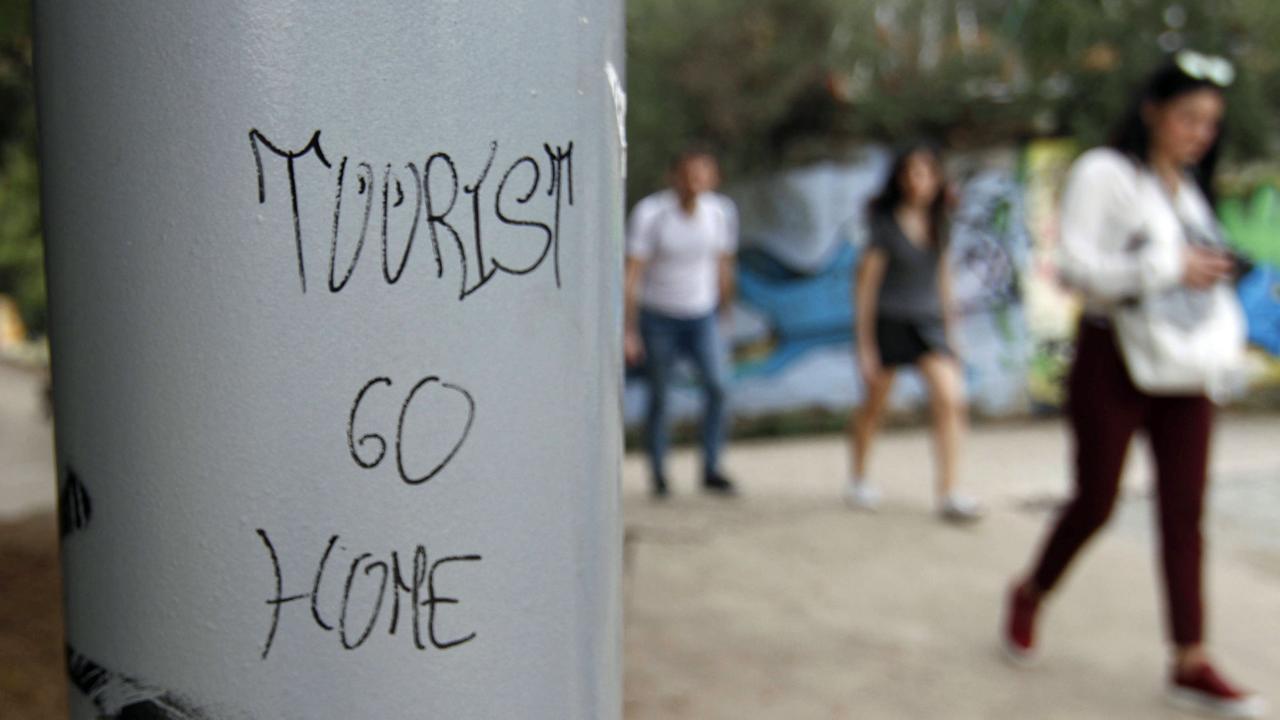 Graffiti "Tourist go home" an einer Säule in Barcelona.