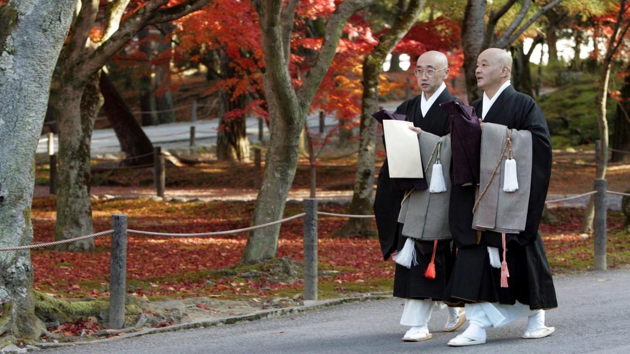 Buddhistische Priester laufen durch einen Garten des Nanzen-ji-Tempels in Kyōto, einem der bekanntesten Tempel des Rinzai-Zen.