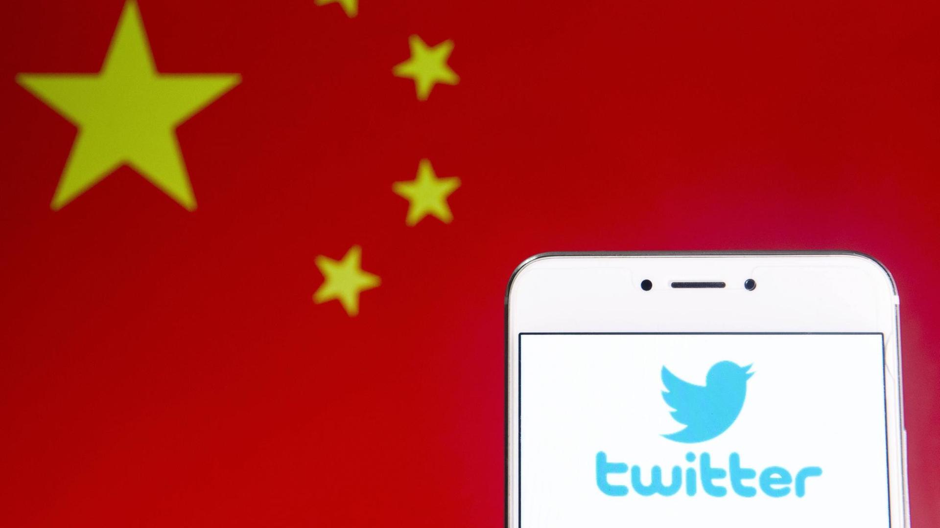 Die Flagge der Volksrepublik China neben dem Logo von Twitter auf einem Smartphone