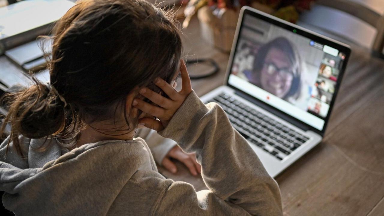 Eine Schülering sitzt am Laptop und unterhält sich mit ihren Schulkameraden und der Lehrering im gemeinsamen Videochat.