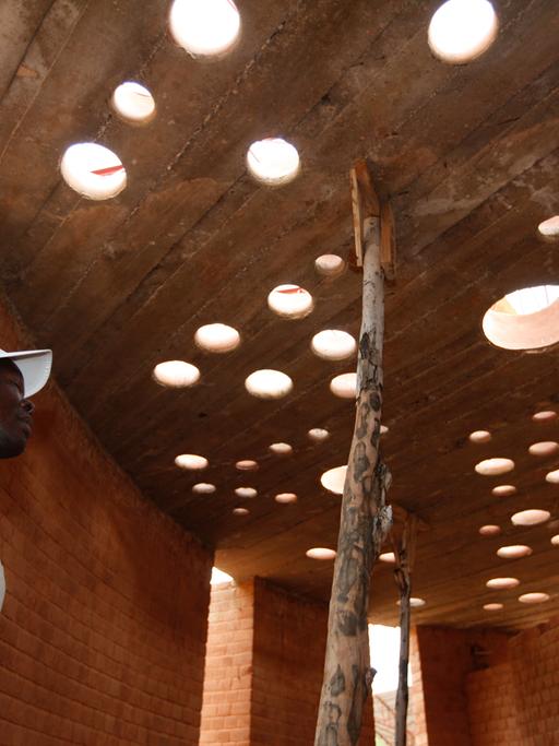 Der Architekt Francis Kéré begutachtet in dem burkinischen Dorf Gando den Baufortschritt an einem Bibliotheksgebäude.