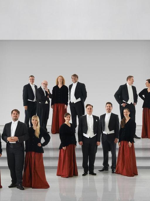 Der Chor steht in schwarz-roter Chorkleidung in einem hellen Raum.