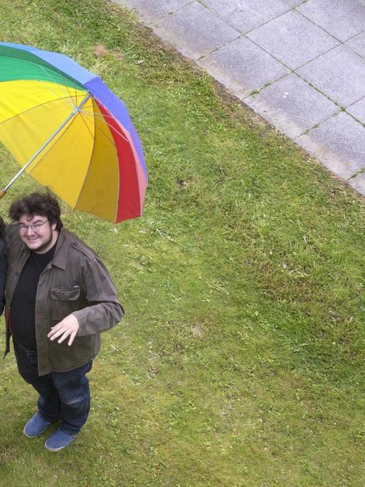 Luftaufnahme von Devid Striesow und Axel Ranisch mit einem bunten Regenschirm.