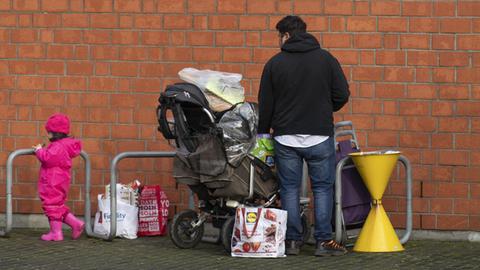 Nachdem sie sich bei der Tafel in der Kirche St. Lioba mit Nahrungsmitteln versorgt haben stehen ein Mann und ein kleines Kind mit vollgepackten Tüten im Freien. Zu den Kunden der Tafeln gehören neben Rentnern auch ganze Familien und alleinstehende Frauen mit ihren Kindern.