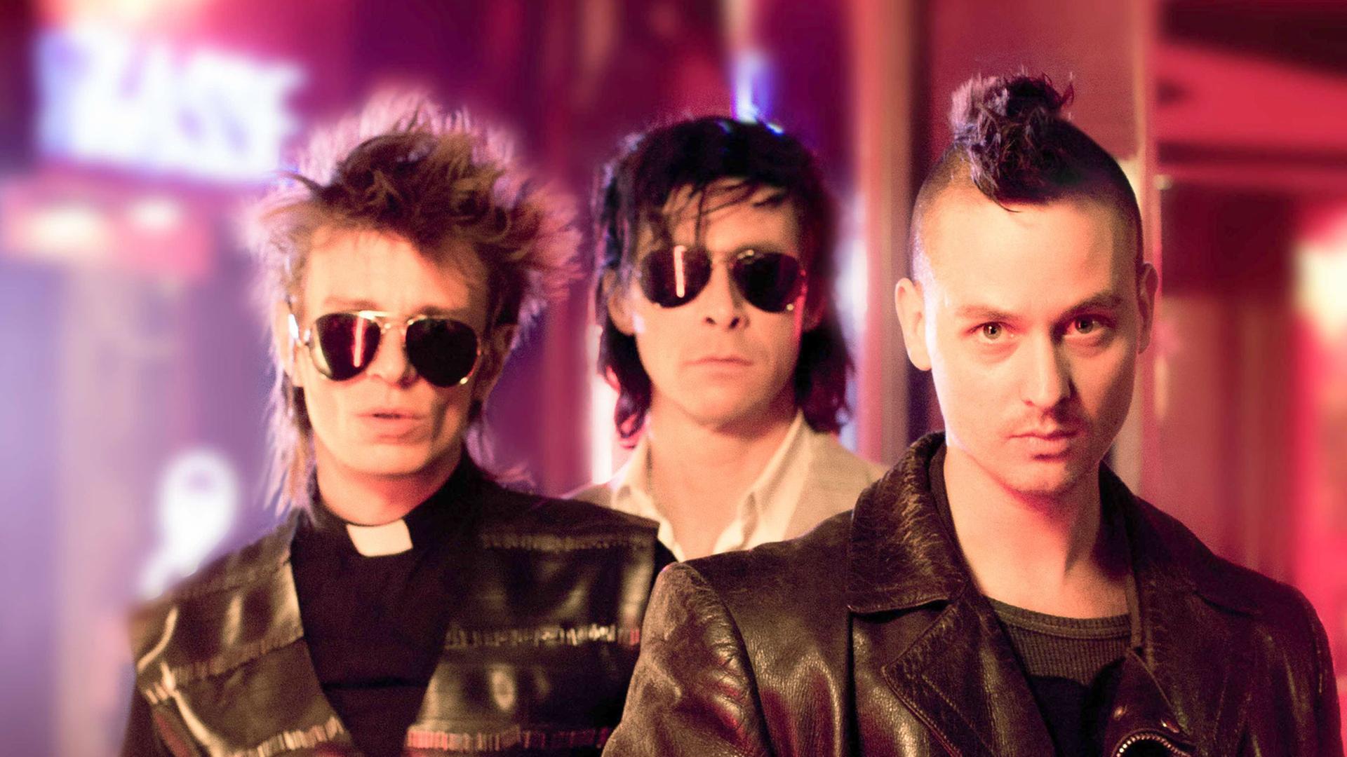 Die Schauspieler Alexander Scheer (als Blixa Bargeld, l-r), Marc Hosemann (als Nick Cave) und Tom Schilling (als Robert) in einer Szene des Films "Tod den Hippies - Es lebe der Punk!".