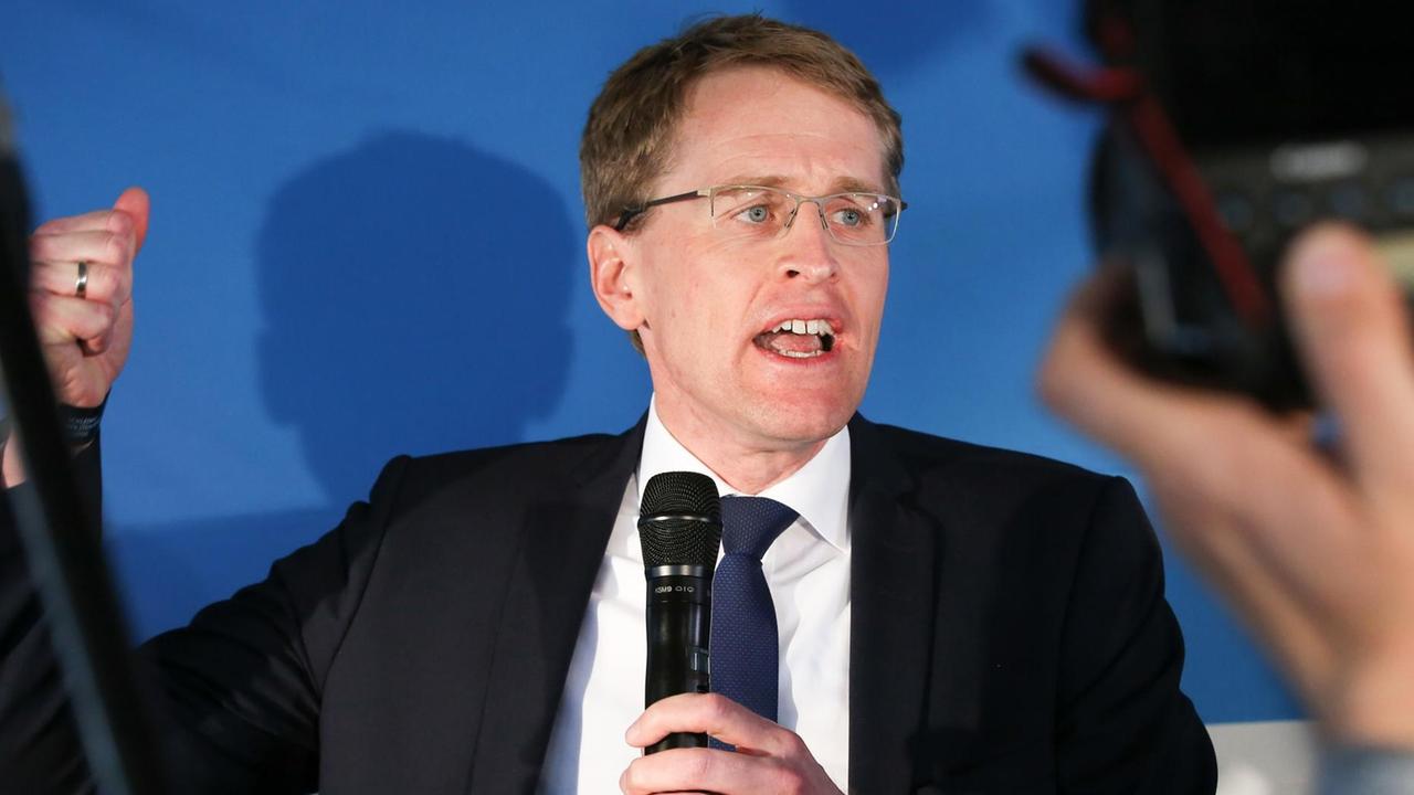 Günther auf der Bühne vor Kameras, mit Mikrofon in der Hand und gestikulierend.