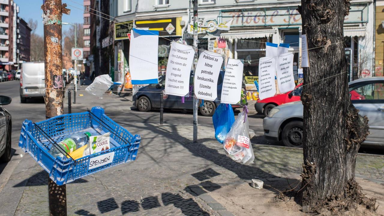 Ein Spendenzaun für Obdachlose in Berlin-Kreuzberg: Pfandflaschen liegen in einer Box, Essen hängt in einer Plastiktüte an einem Seil.