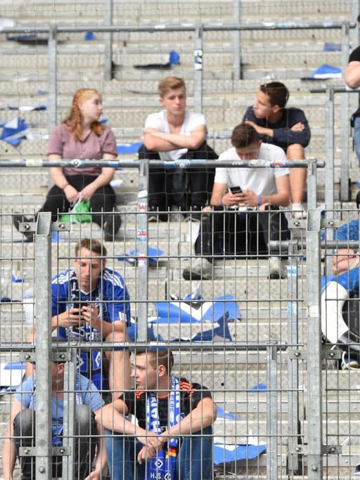 12.05.2018, Hamburg. Fußball: Bundesliga, 34. Spieltag, Hamburger SV - Borussia Mönchengladbach im Volksparkstadion. Fans von Hamburg sitzen nach Spielende traurig auf der halbleeren Tribüne. Der Hamburger SV steigt erstmals in seiner Vereinsgeschichte aus der Fußball-Bundesliga ab. Foto: Daniel Bockwoldt/dpa | Verwendung weltweit