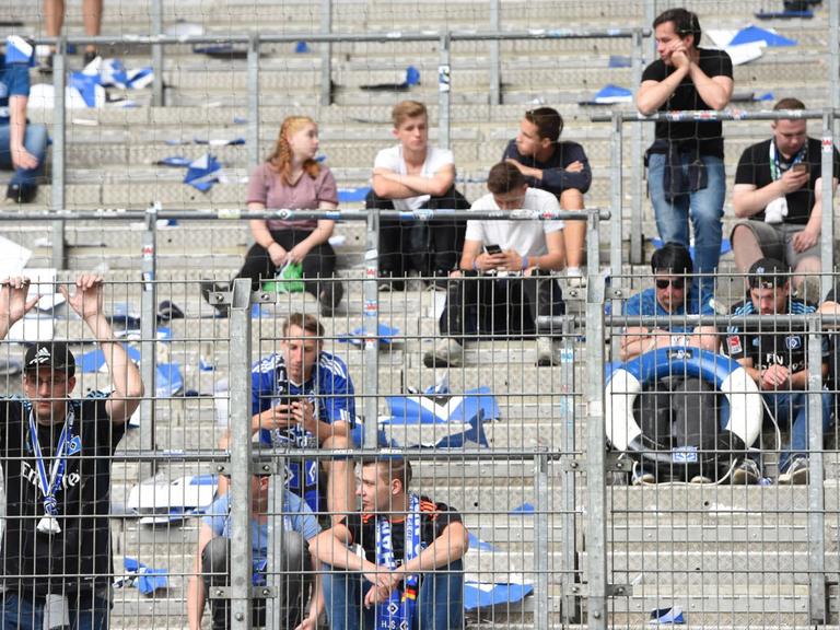 12.05.2018, Hamburg. Fußball: Bundesliga, 34. Spieltag, Hamburger SV - Borussia Mönchengladbach im Volksparkstadion. Fans von Hamburg sitzen nach Spielende traurig auf der halbleeren Tribüne. Der Hamburger SV steigt erstmals in seiner Vereinsgeschichte aus der Fußball-Bundesliga ab. Foto: Daniel Bockwoldt/dpa | Verwendung weltweit