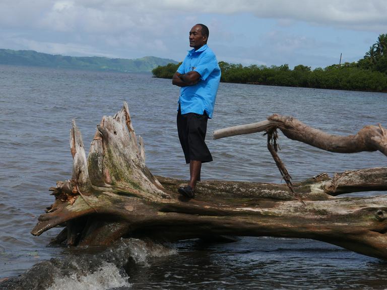 Sailosi Ramatu, Oberhaupt des Dorfs Vunidogoloa auf den Fidschi-Inseln, steht auf einem umgefallenen Baum am Strand.