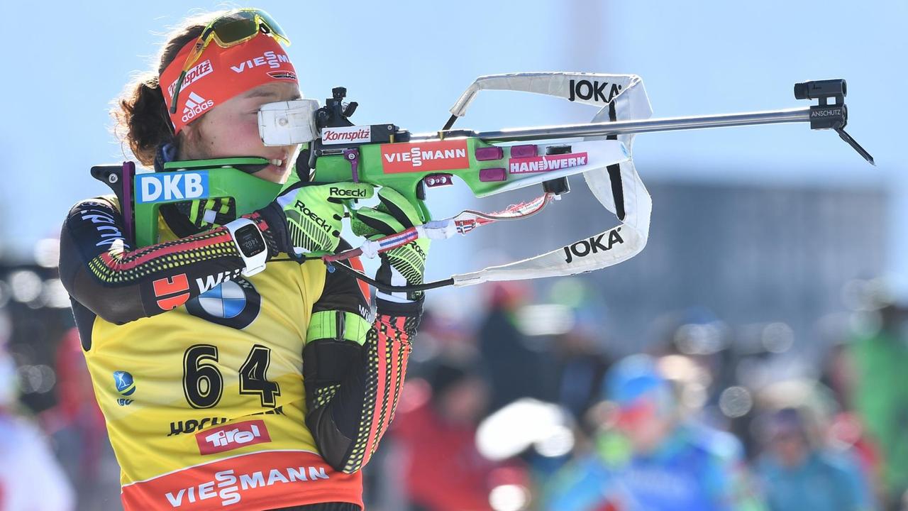 Die Biathlin Laura Dahlmeier hat ihr Gewehr im Arm und schießt auf eine Zielscheide. 