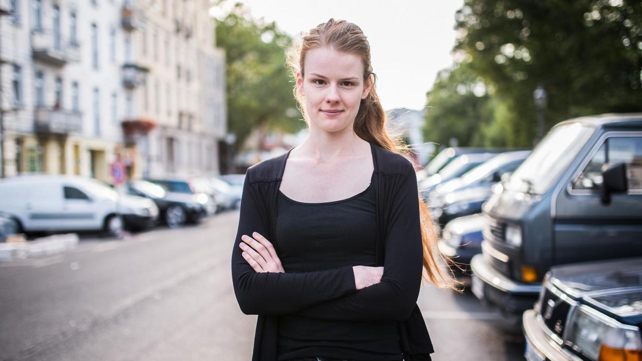 Die Berliner CDU-Politikerin Jenna Behrends steht auf einer Straße, rechts und links parkende Autos