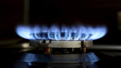 Eine Gasflamme leuchtet blau auf dem Kochfeld eines Gasherdes.