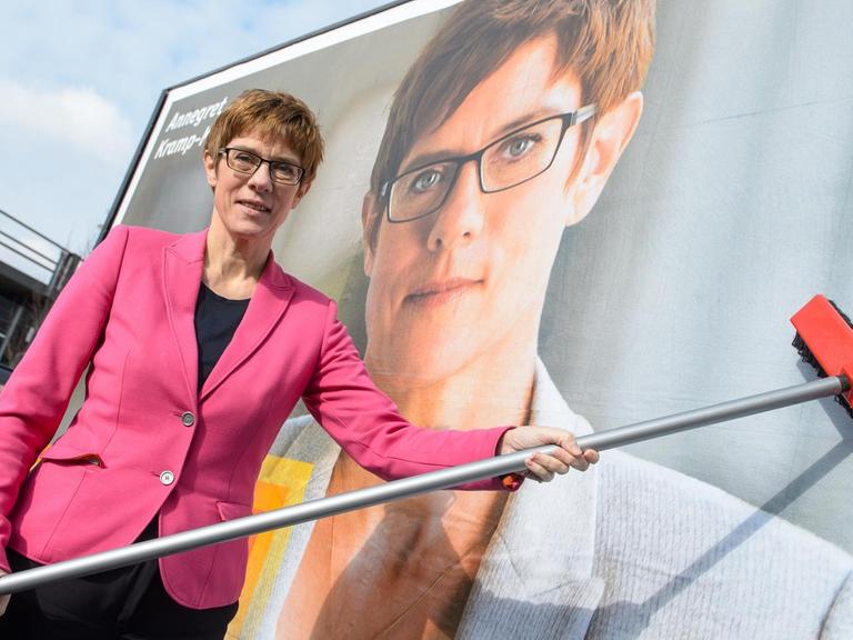 Die saarländische Ministerpräsidentin Annegret Kramp-Karrenbauer (CDU) klebt am 09.02.2017 in Saarbrücken mit einem Besen symbolisch das letzte Teil ihres Plakatmotivs für die Landtagswahl an, das sie zuvor enthüllte.