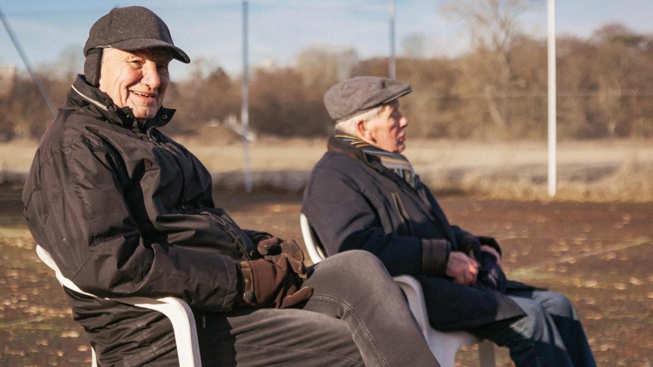 Zwei ältere Herren sitzen am Spielfeldrand 
