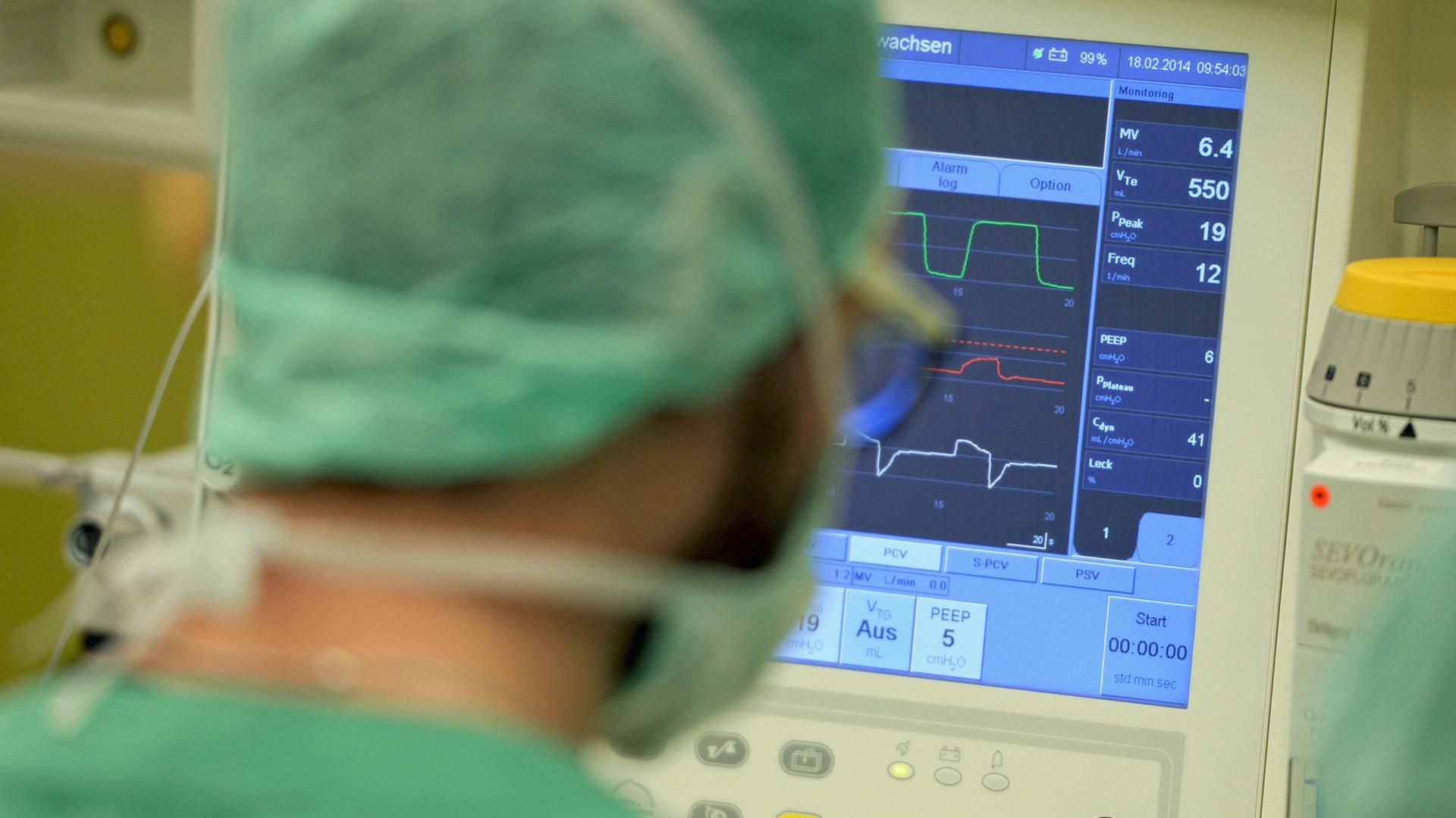 Ein Mediziner schaut am 18.02.2014 in einer Klinik in Baden-Württemberg während einer Operation auf einen Überwachungs-Monitor.