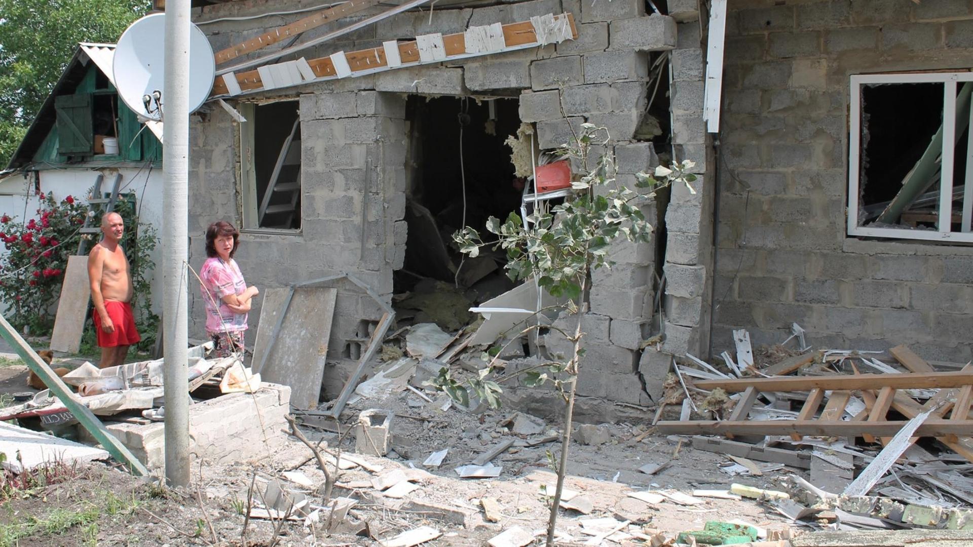 Ein Mann und eine Frau am 19.06.2015 vor einem bombardierten Haus.