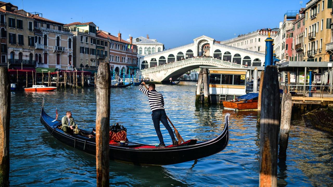 Ein Gondoliere mit seiner Gondel vor der Rialto-Brücke in Venedig.
