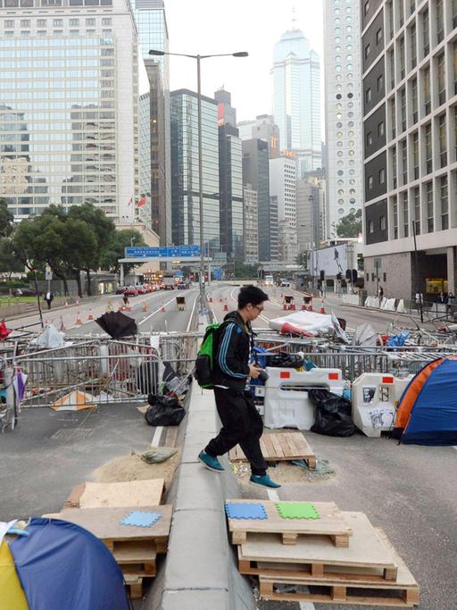 Metallzäune, Paletten und Zelte blockieren eine sechsspurige Straße zwischen Hochhäusern.