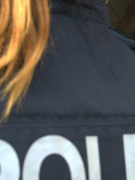 Eine Polizistin klebt am 27.10.2015 in Berlin ein Flugblatt mit dem Foto eines Mannes an eine Haustür.