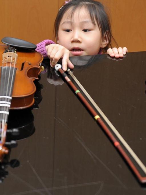 Früh übt sich: Die fünfjährige Emely nimmt sich ihre Kindergeige von einem Klavier.