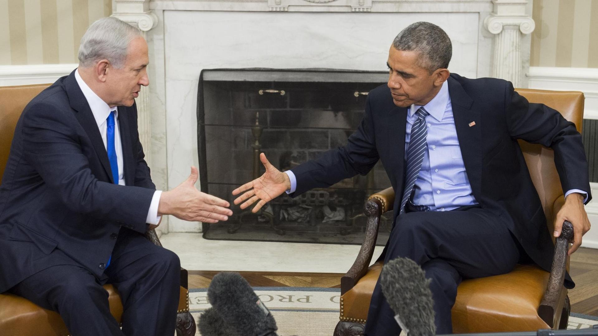 Israels Ministerpräsident Benjamin Netanjahu (l.) und US-Präsident Barack Obama reichen sich sitzend die Hand.
