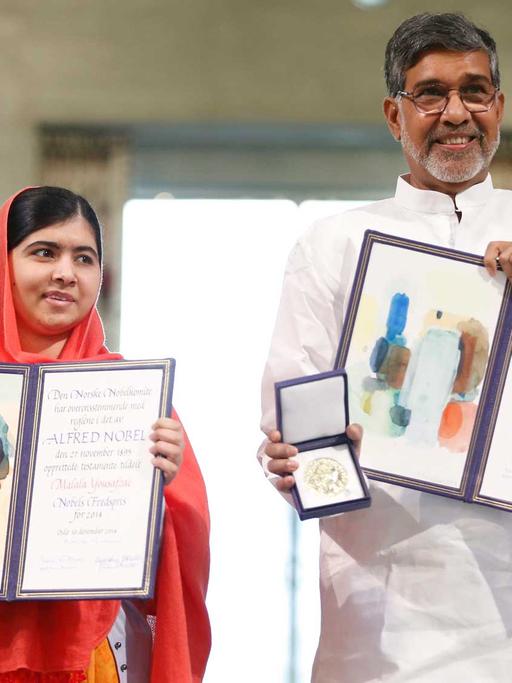 Malala Yousafzai (links) und Kailash Satyarthi zeigen ihre Nobelpreisurkunden und -Medaillen während der Preiszeremonie.
