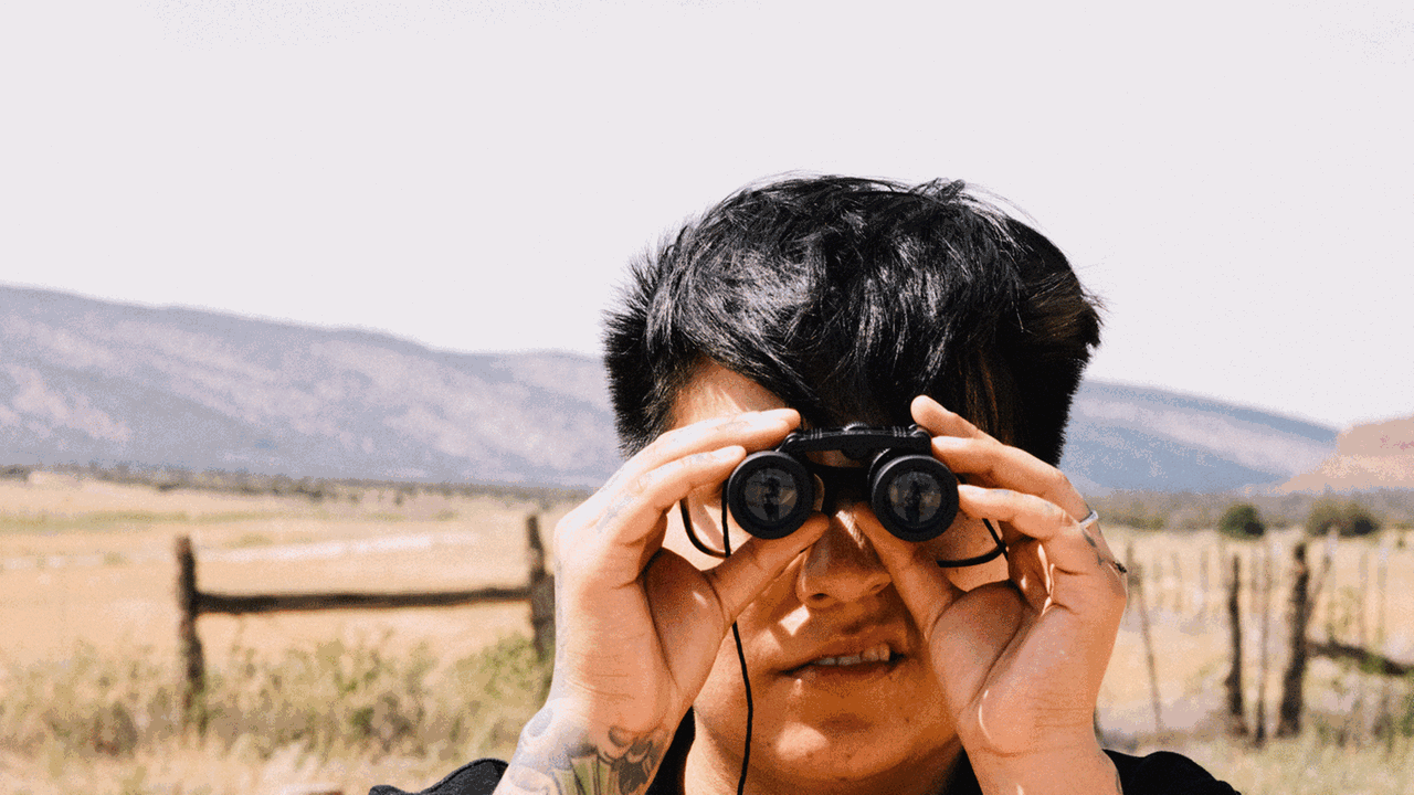 Serie Observateur - Ein junger Mann schaut mit einem Fernglas in die Kamera. Serie Observateur - Ein junger Mann schaut mit einem Fernglas in die Kamera.