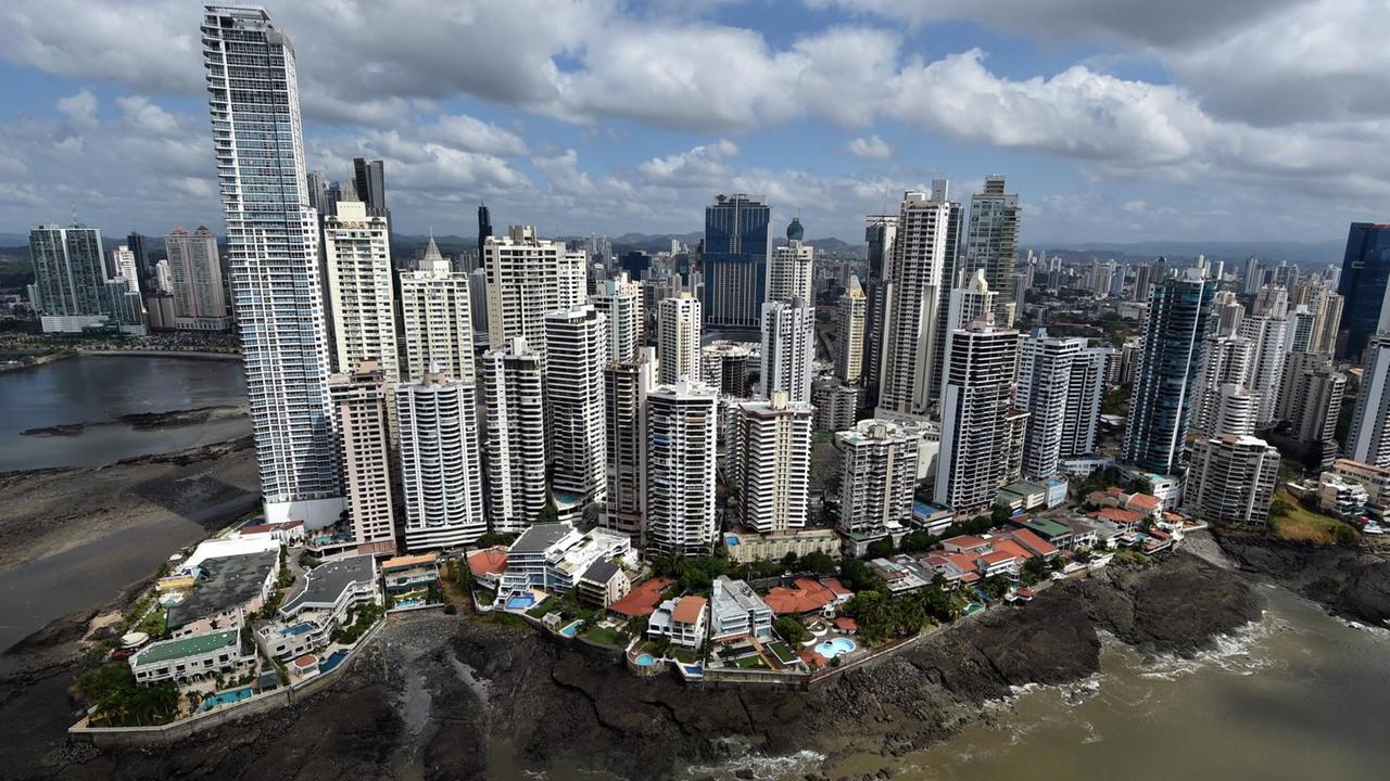 Das Bild zeigt zahlreiche Hochhäuser am Meer. Direkt an der felsigen Küste sind Villen mit blauen Pools.