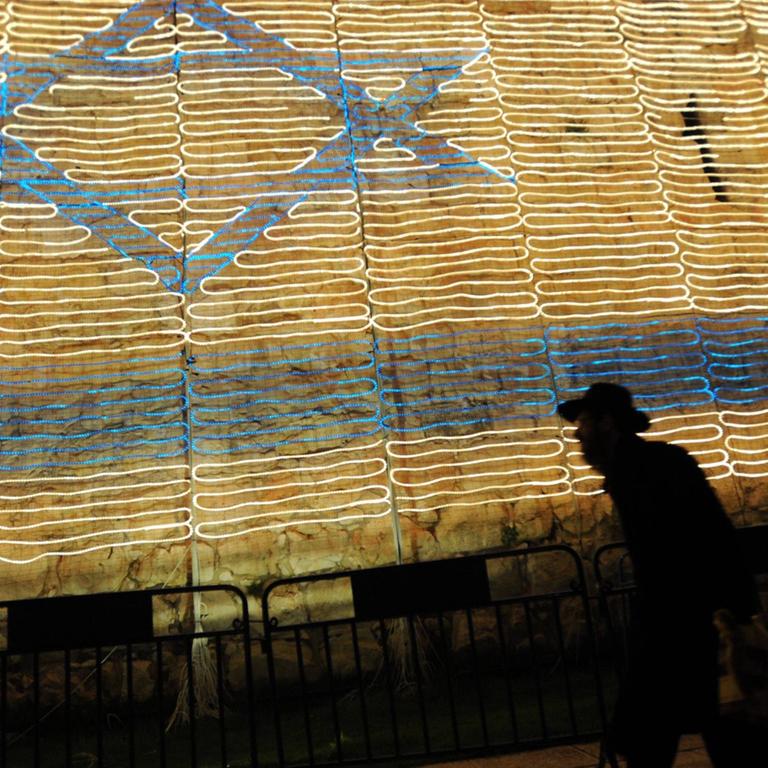 Es ist der 9. Mai 2011, der Unabhängigkeitstag in Israel und ein orthodoxer Jude mit Hut läuft an einer Mauer entlang, im Hintergrund die israelische Flagge, bestehend aus Lichterketten in der alten Stadt Jerusalem. Sie feiern den 63. Geburtstag des Beginns eines jüdischen Staates.
