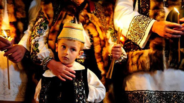 Kind in traditioneller Kleidung im Ostergottesdienst einer rumänisch-orthodoxen Kirche im Dorf Cacica, Rumänien.