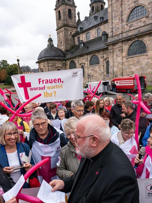 Hessen, Fulda: Kardinal Reinhard Marx (M), Vorsitzender der Deutschen Bischofskonferenz, trifft vor dem Fuldaer Dom zu Beginn der Herbstvollversammlung der Deutschen Bischöfe mit Demonstrantinnen der Katholischen Frauengemeinschaft Deutschlands zusammen, die mehr Geschlechtergerechtigkeit in der Kirche fordern.