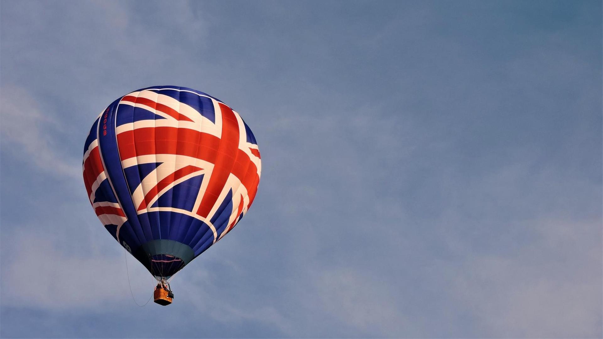 Ein Heißluftballon, bedruckt mit dem Union Jack, vor blauen Himmel.
