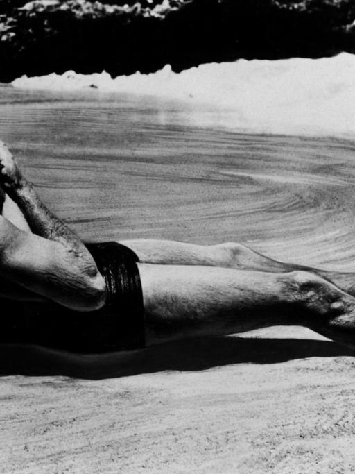 Ein Film-Still zeigt die Schauspielerin Deborah Kerr und Filmpartner Burt Lancaster bei einem Kuss am Strand von Hawaii von einer Welle umspült