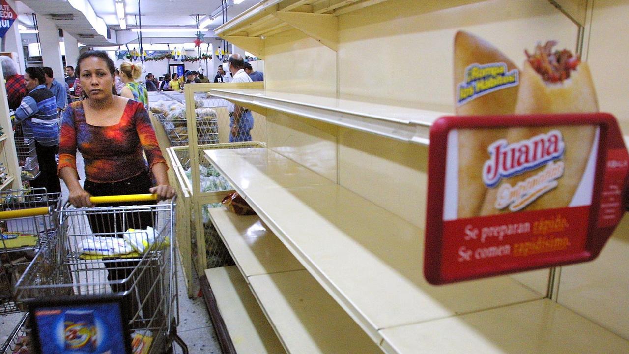 Eine Frau fährt mit einem Einkaufswagen an leeren Regalen in einem Supermarkt in Maracaibo in Venezuela 