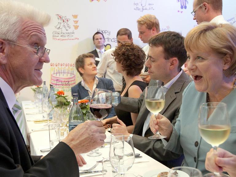 Der Ministerpräsident von Baden-Württemberg, Winfried Kretschmann (Grüne) und Bundeskanzlerin Angela Merkel (CDU) stoßen am Donnerstag (05.07.2012) auf der Stallwächter-Party, das Sommerfest des Landes Baden-Württemberg in Berlin, mit Wein an.
