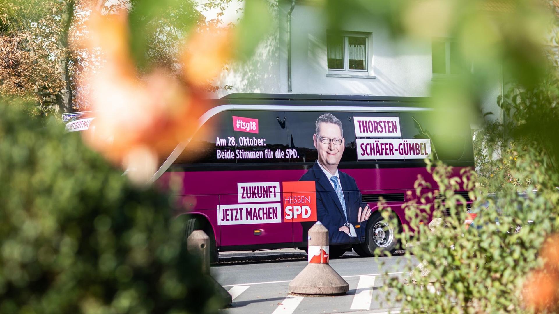 Im Vordergrund verschwommene Büsche, im Hintergrund der Wahlkampfbus von Thorsten Schäfer-Gümbel.