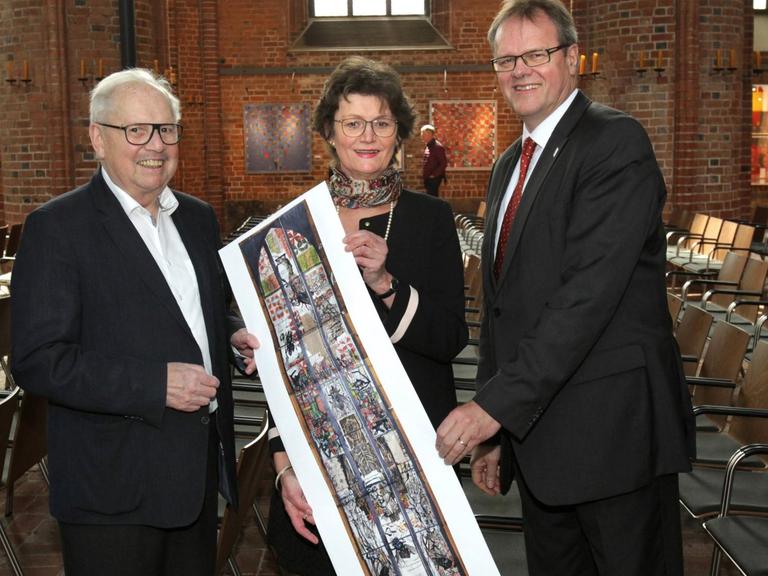 Kirchenvorstand Reinhard Scheibe, Marktkirchenpastorin Hanna Kreisel-Liebermann und Stadtsuperintendent Hans-Martin Heinemann (v. li.) mit dem Entwurf für das Lüpertz-Kirchenfenster.