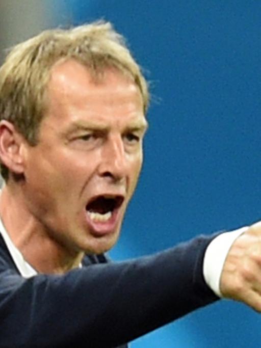 Jürgen Klinsmann reckt den rechten Daumen hoch und schreit über den Platz
