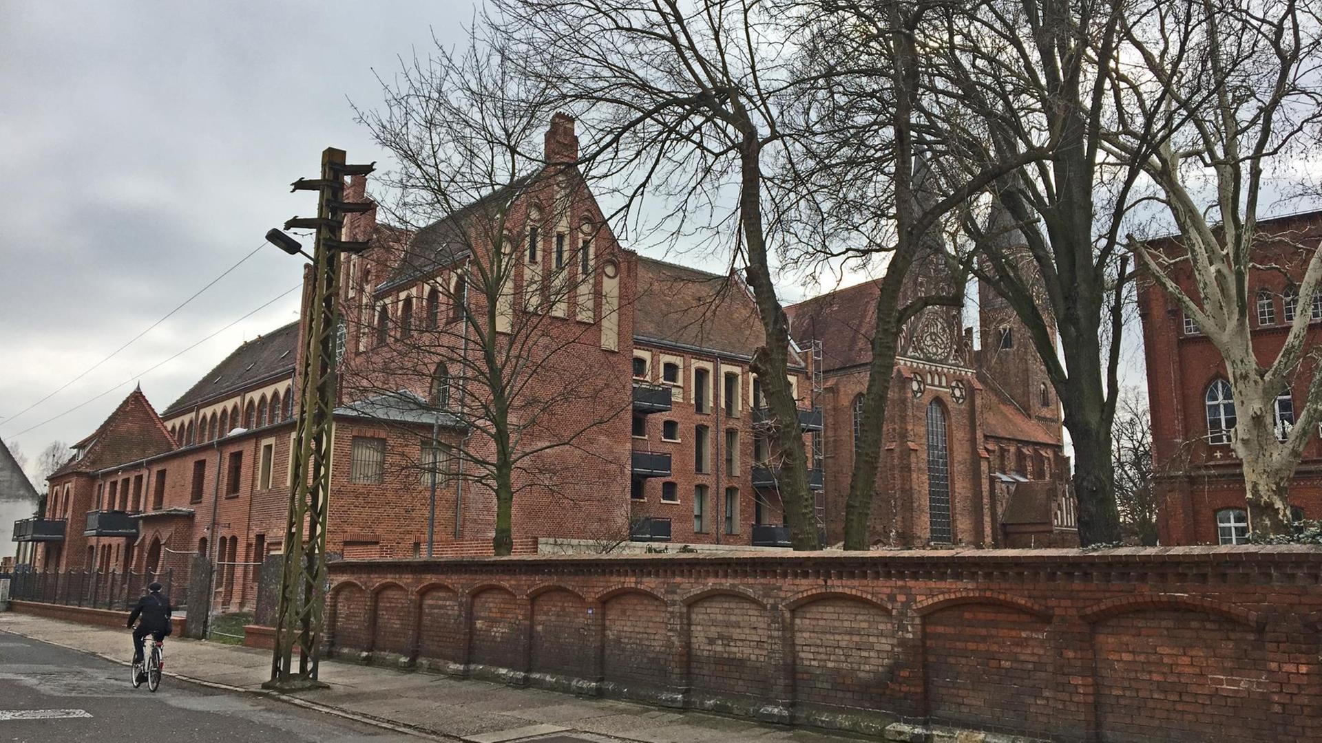 Zu sehen ist das umgebaute Gefängnis mit roten Backsteinen von der Straße aus.