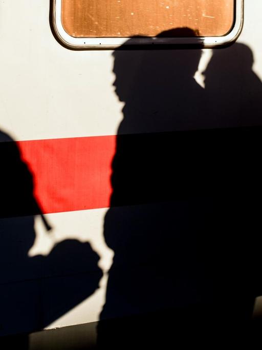 An einem stehenden Zug-Waggon zeichnen sich Schatten von Flüchtlingen ab. 