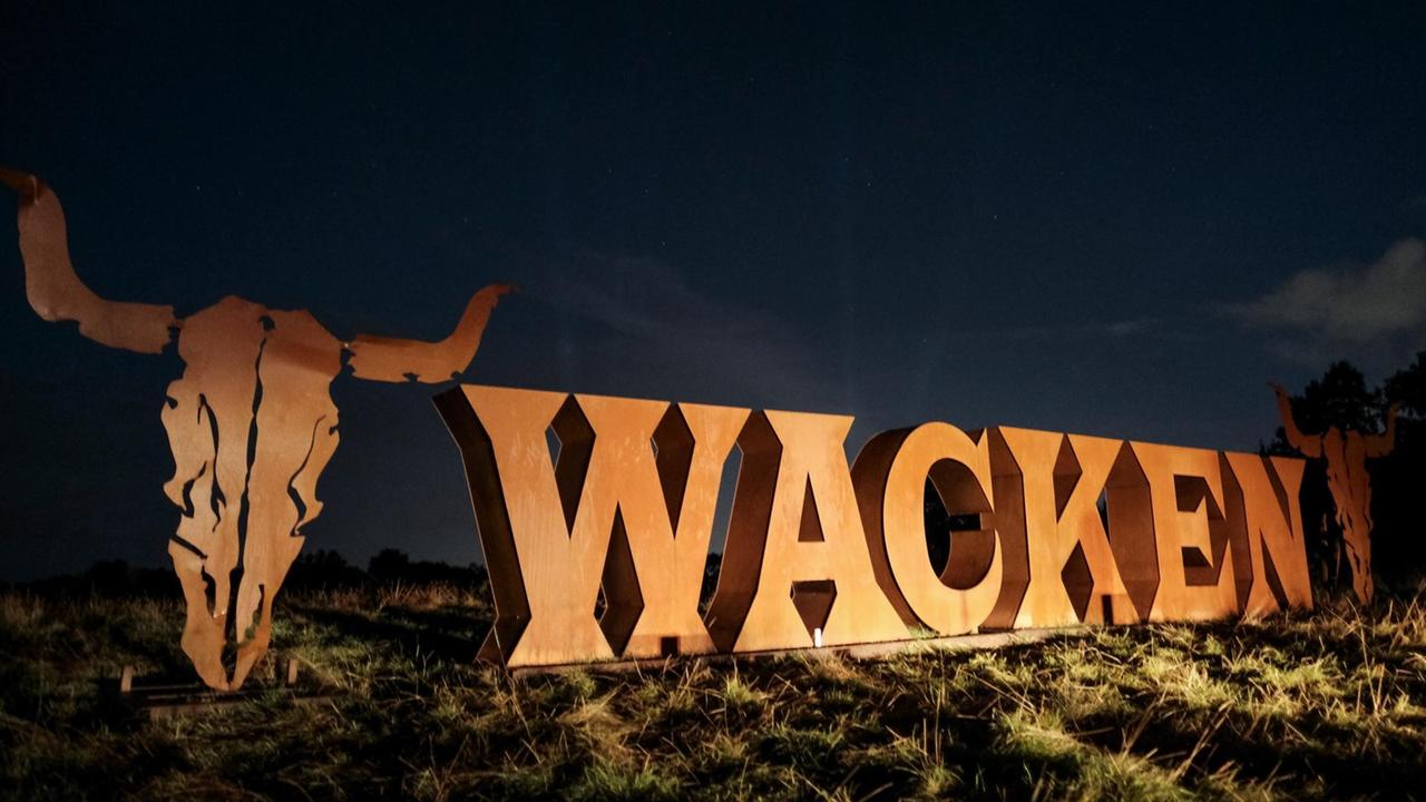 Autoscheinwerfer werfen Licht auf das Festivallogo des Wacken Open Air.