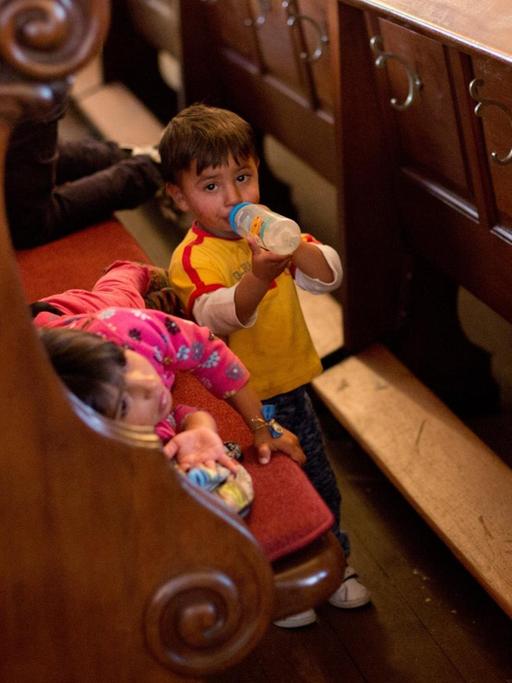 Zwei Roma-Kinder zwischen Kirchenbänken.