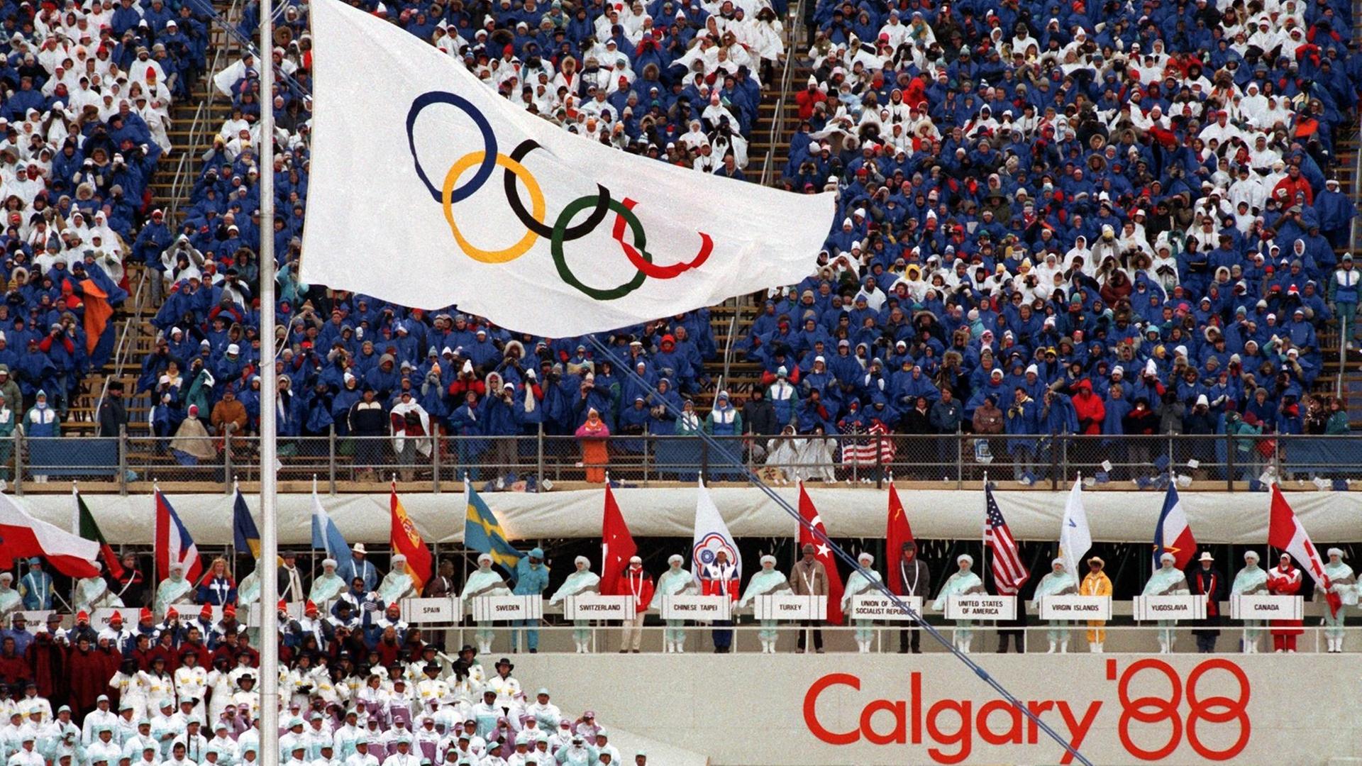 Die Fahne mit den Olympischen Ringen weht im McMahon-Stadion - aufgenommen während der Eröffnungsfeier der Olympischen Winterspiele 1988 in Calgary, Kanada.