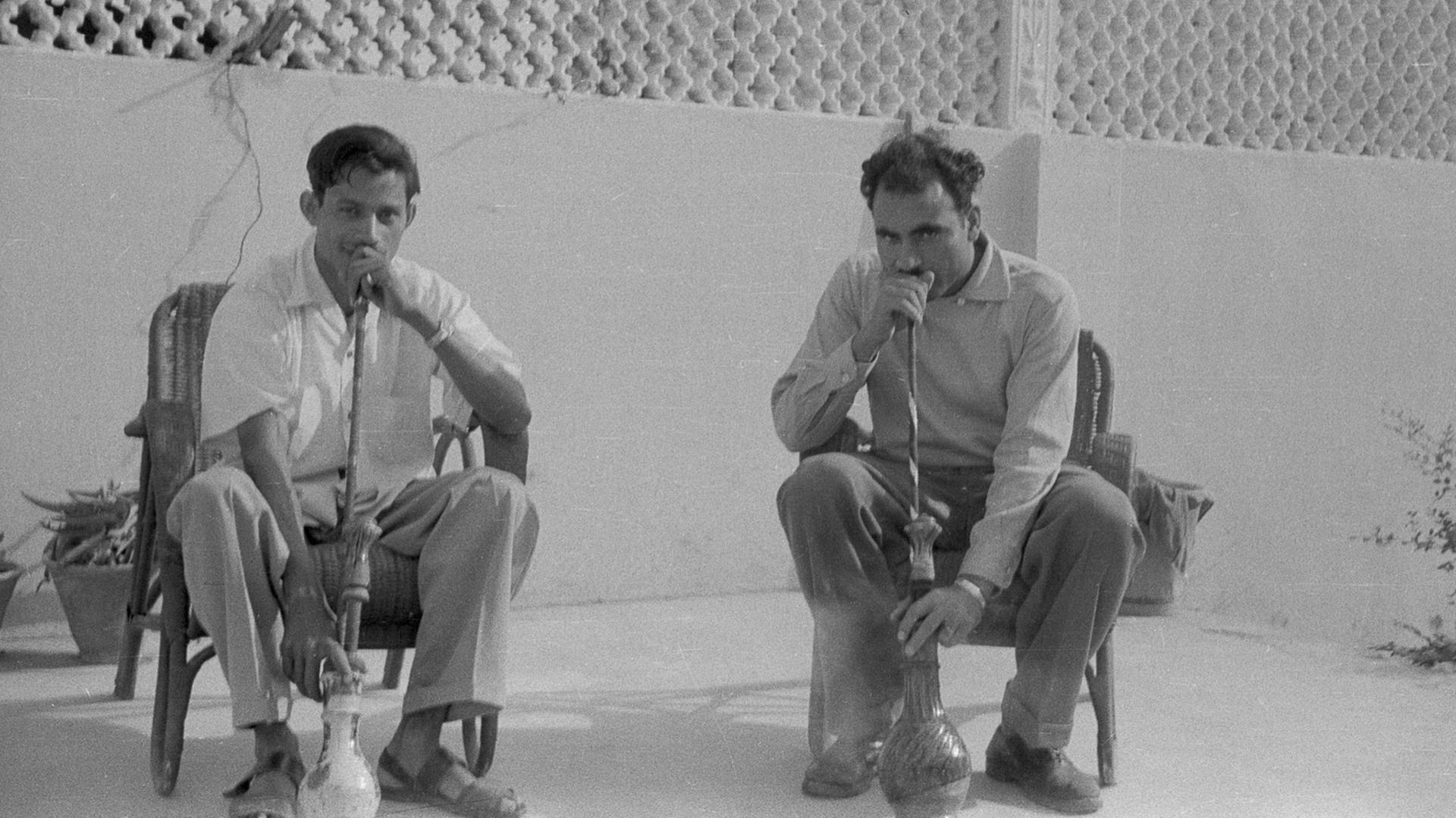 Zwei Männer im Pakistan der 1960er-Jahre rauchen Wasserpfeife.