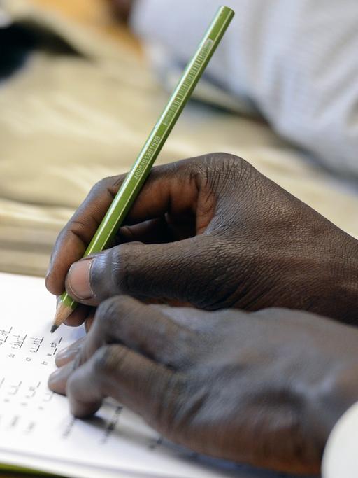 Ein Schüler schreibt beim Deutschunterricht für Asylbewerber auf ein Arbeitsblatt.