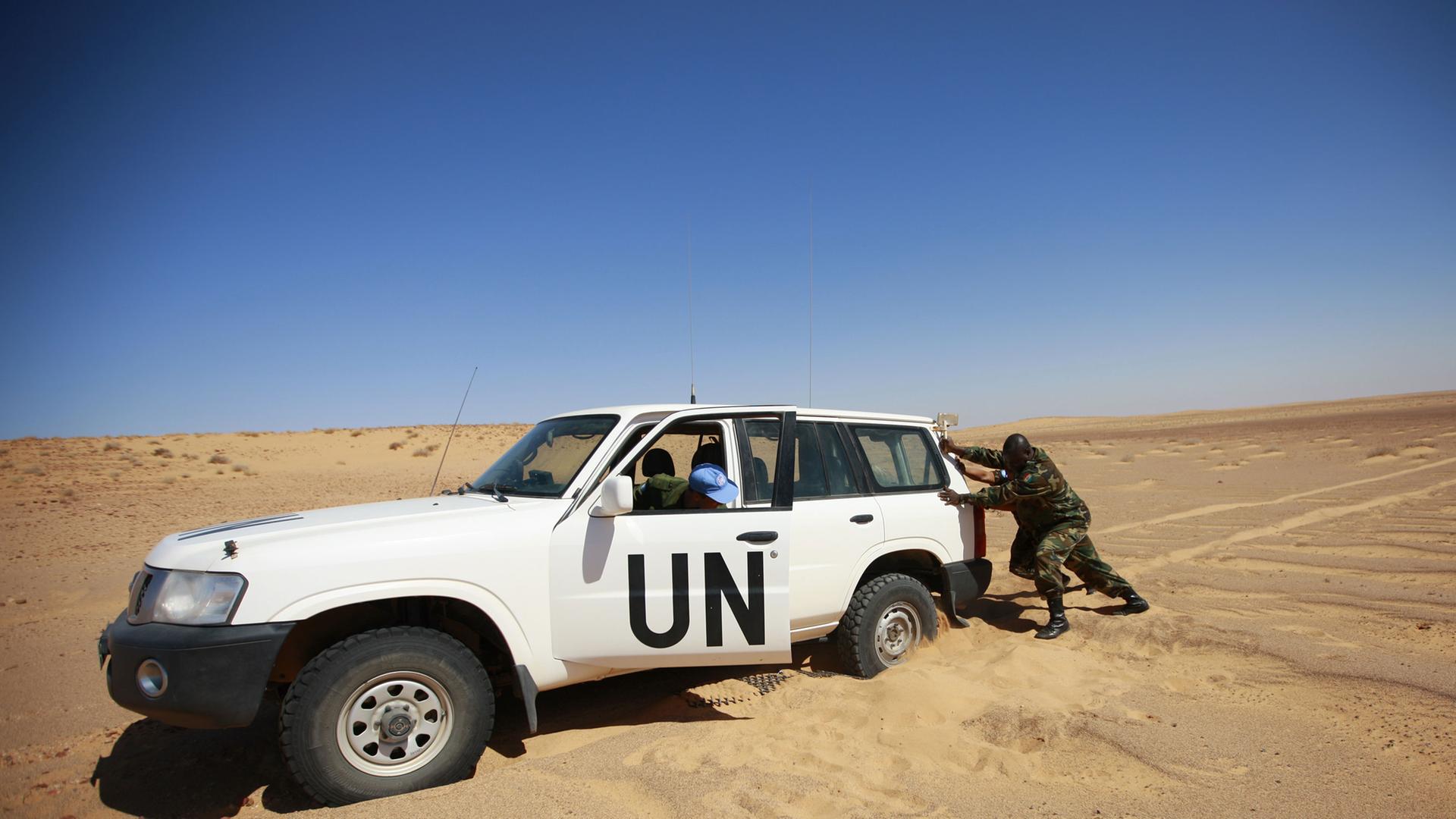 Mitglieder der UN Mission for the Referendum in Western Sahara (MINURSO), versuchen ihr Auto aus dem Sand zu bewegen.
