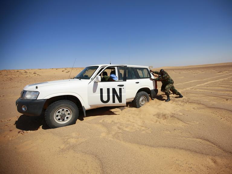 Mitglieder der UN Mission for the Referendum in Western Sahara (MINURSO), versuchen ihr Auto aus dem Sand zu bewegen.